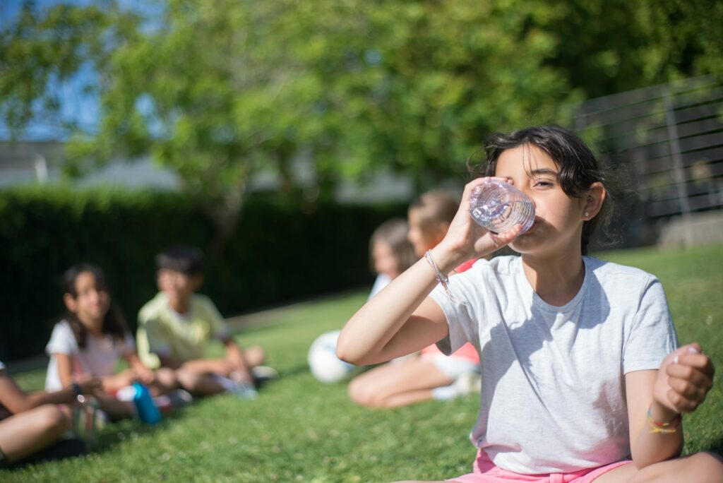A young girl hydrating by drinking some water